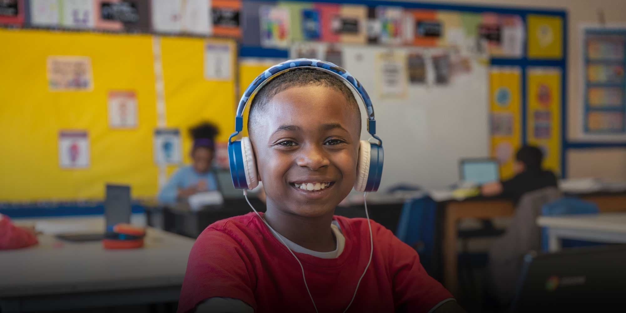 Smiling student with headphones sitting at desk