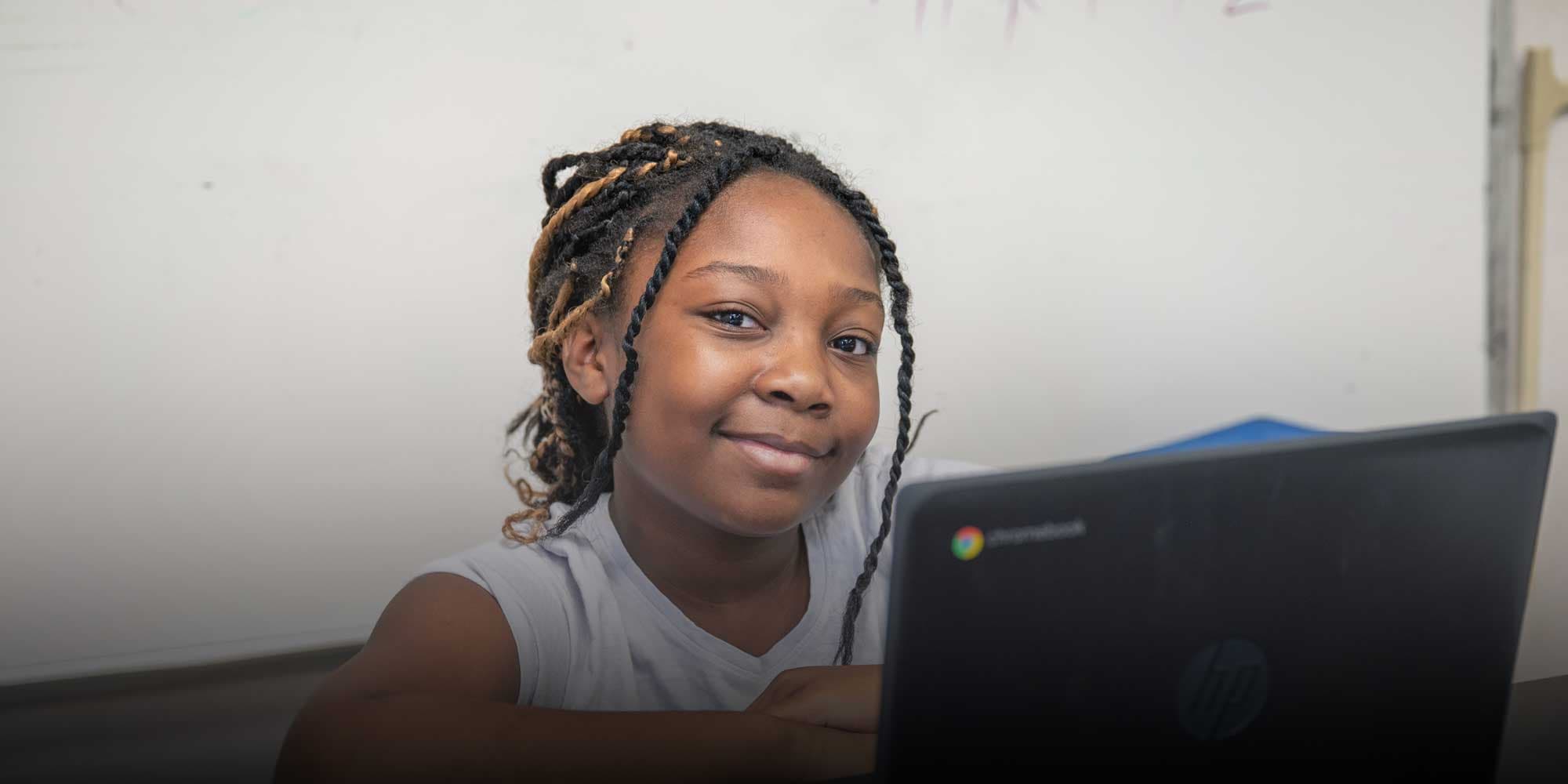 Smiling student sitting at a desk with a laptop.