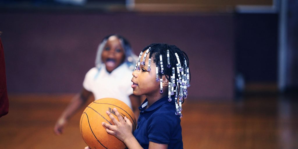 Elementary student holding a basketball in the school gym.